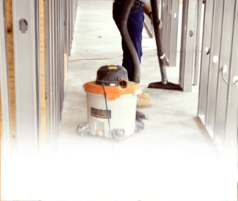 Post-construction cleaning services shown with a professional cleaning using a shop vacuum to clear post-construction dust and debris from a newly remodeled home.