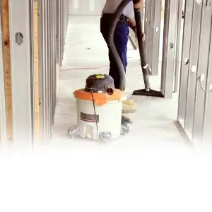 Post-construction cleaning services with a professional cleaner using a shop vacuum to remove dust and debris.