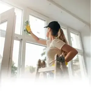 Every-move-in-out-clean-covers-the-full-property: A professional cleaner wiping down a window frame inside a bright room during a move-in or move-out service.